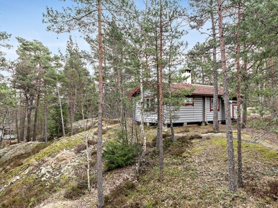 Sagolik tomt med timmerhus bland skärgårdshällar.